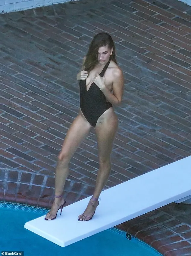 Hailey Bieber looked nothing short of sensational while modeling a plunging black swimsuit during a poolside photoshoot at the Chateau Marmont in West Hollywood