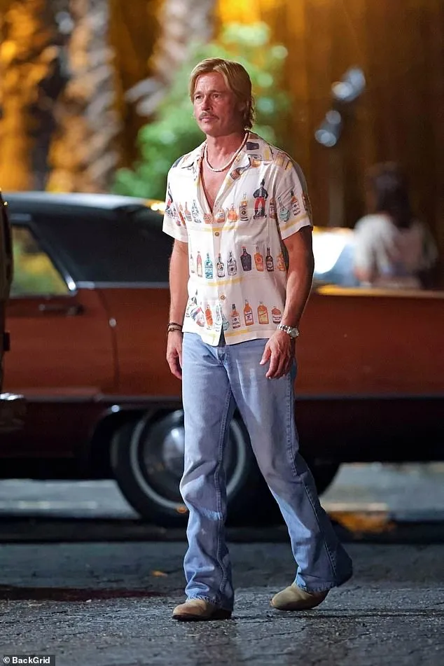 The 61-year-old movie star sported a shag wig fastened by hairstylist Araxi Lindsey over his shaved head while clad in a puka-shell necklace, bottle-patterned shirt, and baggy blue jeans